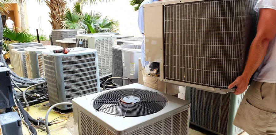 hvac technician removing old rusted broken air conditioners in HVAC at beach condo.